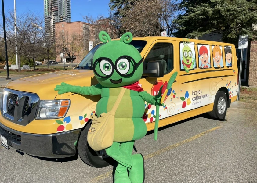 Camille La chenille, la mascotte du conseil devant son bus jaune du CECCE